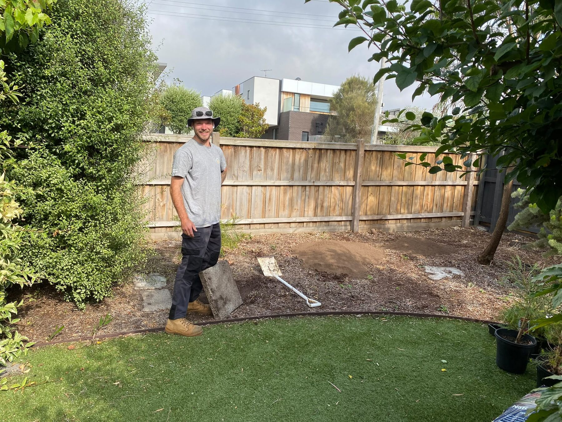 Charlie Mathieson standing in a newly landscaped backyard with fresh turf and garden beds.