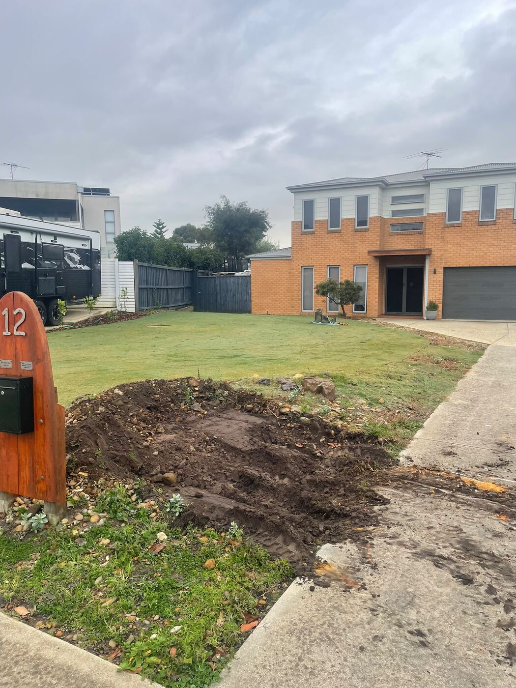 Same front yard before landscaping, with bare dug-over soil near the letterbox.